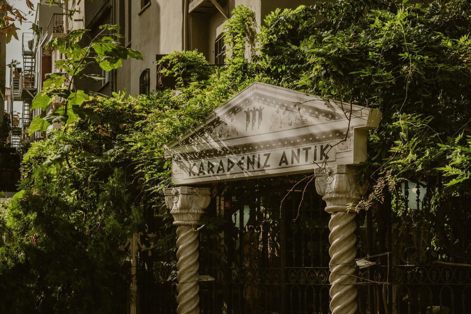 Entrée sculptée d'un atelier d'antiquités dissimulé sous la verdure à Cağaloğlu.