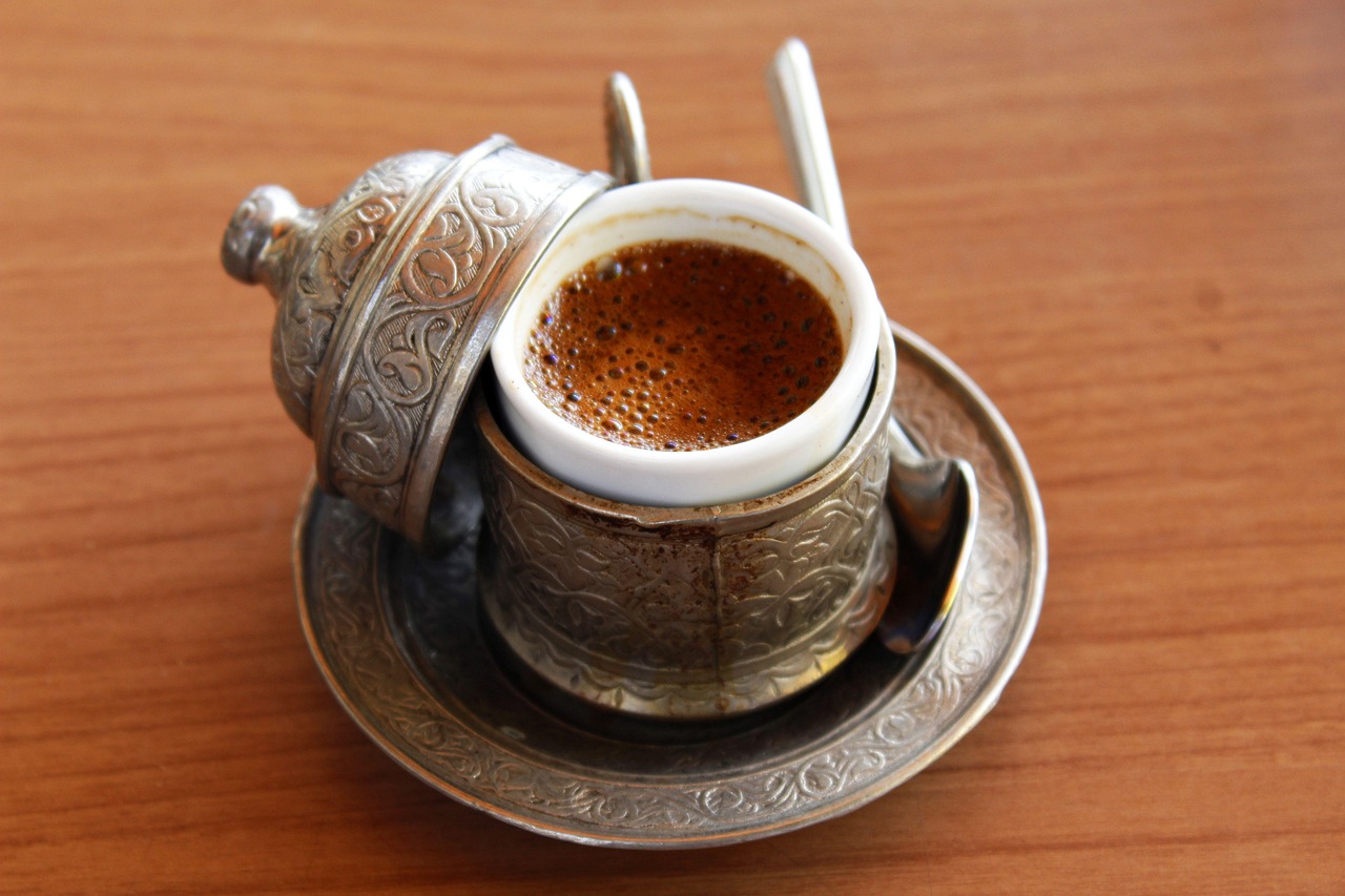 Une tasse de café turc mousseux servie dans un support en métal ciselé traditionnel.