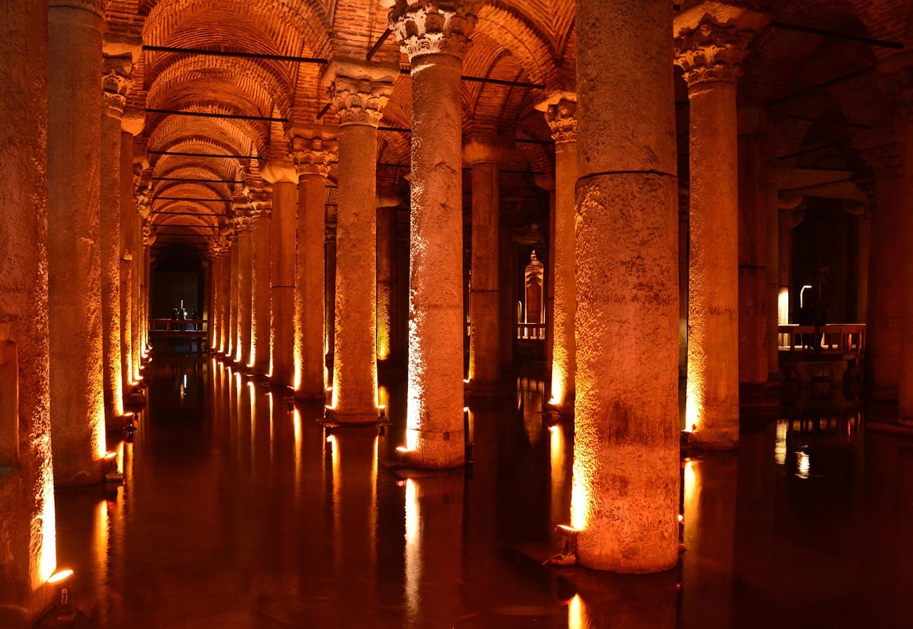 Colonnes antiques illuminées de la Citerne Basilique reflétées dans l'eau en nocturne.