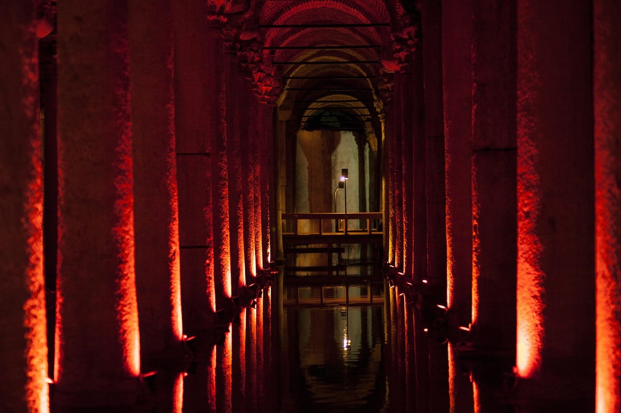 Éclairage nocturne rougeoyant entre les colonnes historiques de la Citerne Basilique.