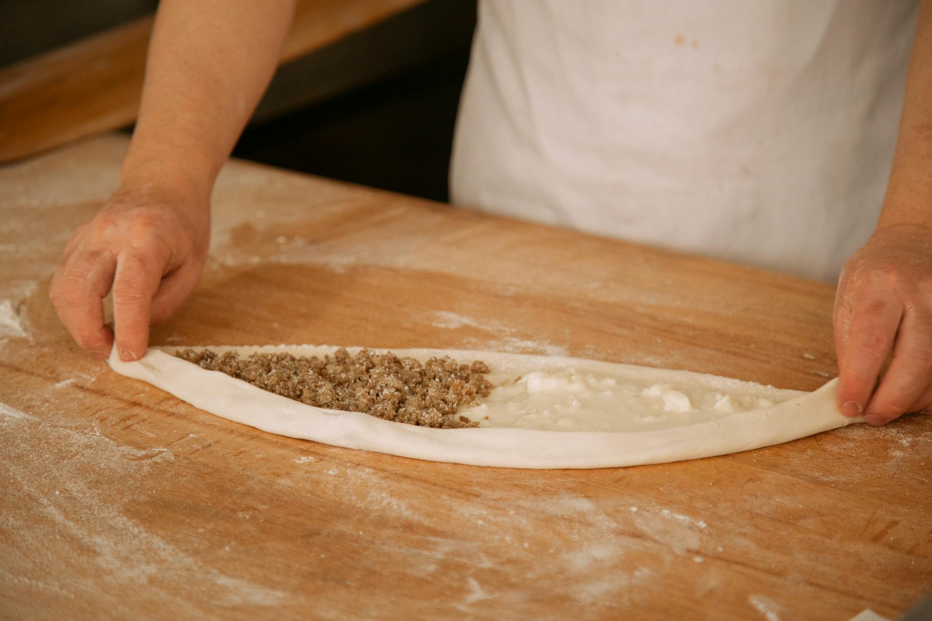 Un cuisinier façonne un pide au beurre garni de viande et de fromage.