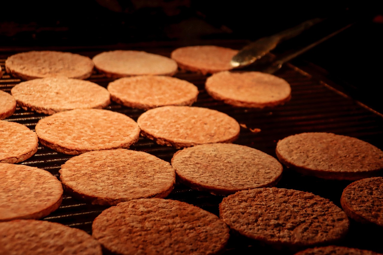 Cuisson de galettes de viande sur une plaque chauffante pour la cuisine nocturne.