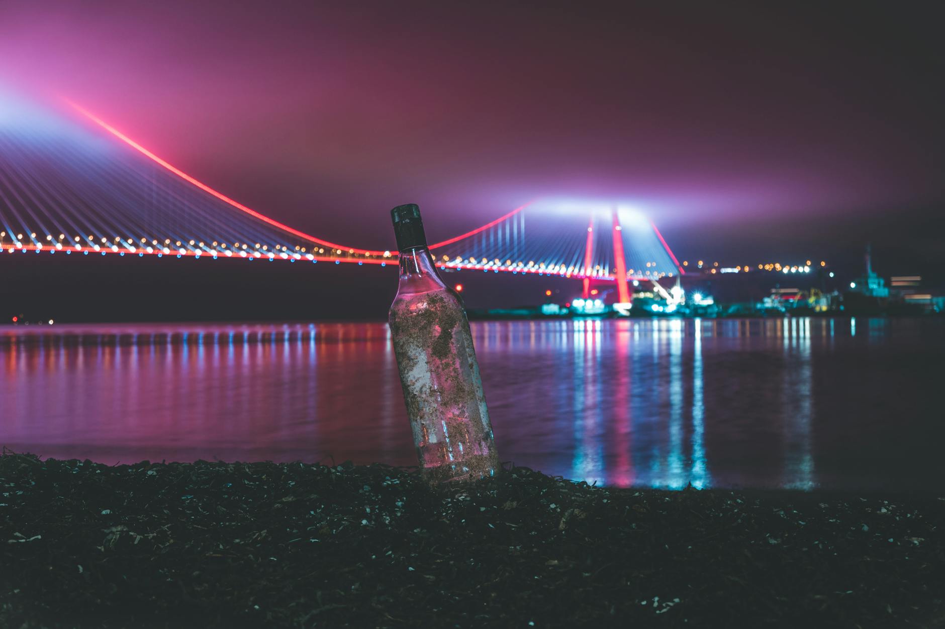 Une bouteille d'eau posée devant un pont illuminé d'Istanbul la nuit.