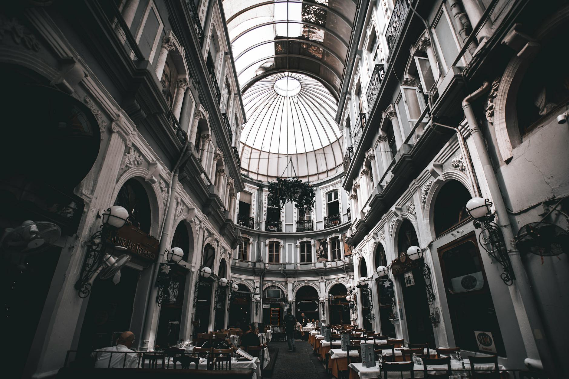 Intérieur d'un passage couvert historique de Beyoğlu à Istanbul, avec un plafond voûté vitré, des balcons et des restaurants installés sous les arcades.