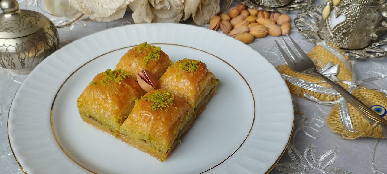 Quatre baklavas à la pistache servis sur une assiette blanche.