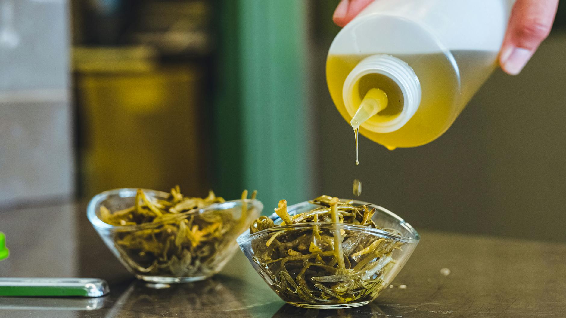 Huile d'olive pure versée sur une salade d'herbes sauvages dans un bol.