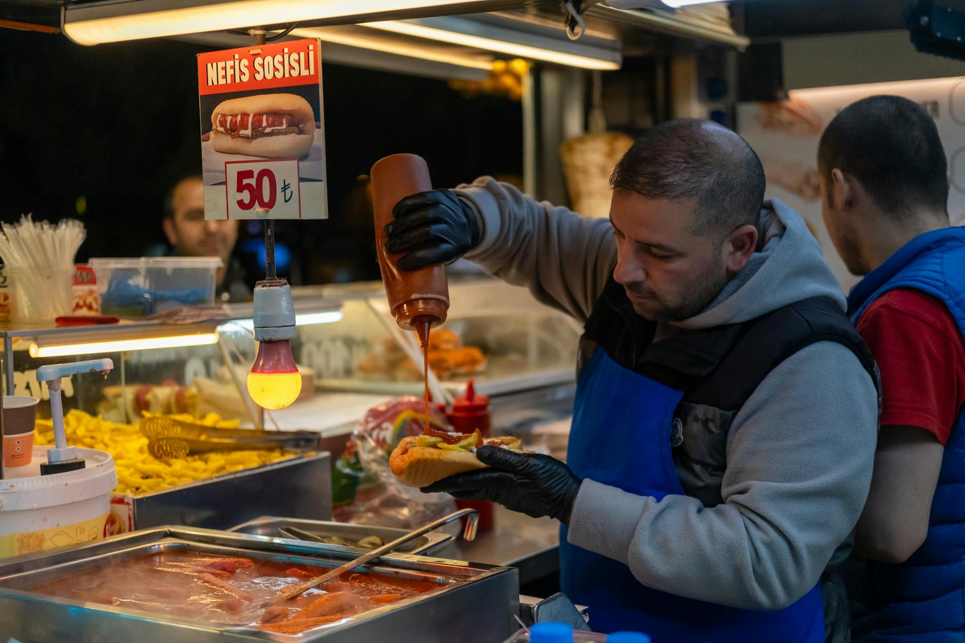 Préparation d'un sandwich à la saucisse dans une échoppe de rue typique d'Istanbul.