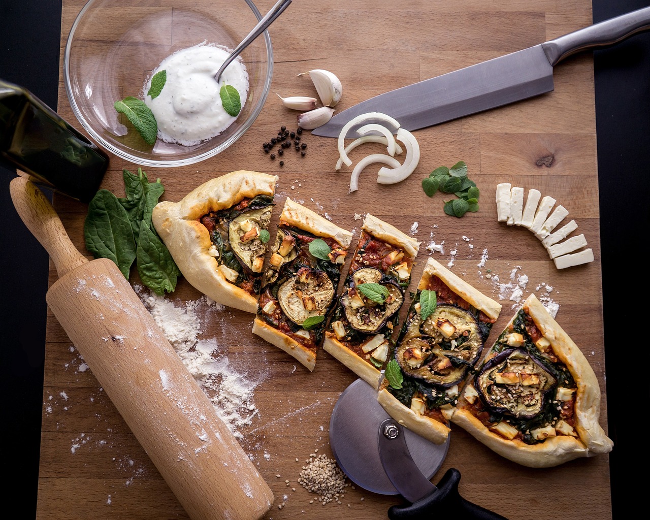 Des tranches de pide aux aubergines et fromage féta disposées sur une planche.