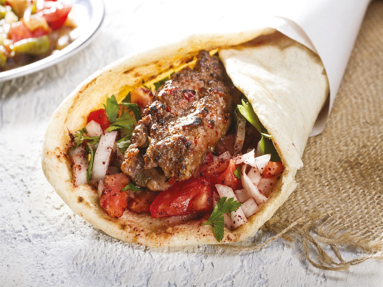 Dürüm kebab épicé enveloppé dans une galette avec oignons et tomates fraîches.