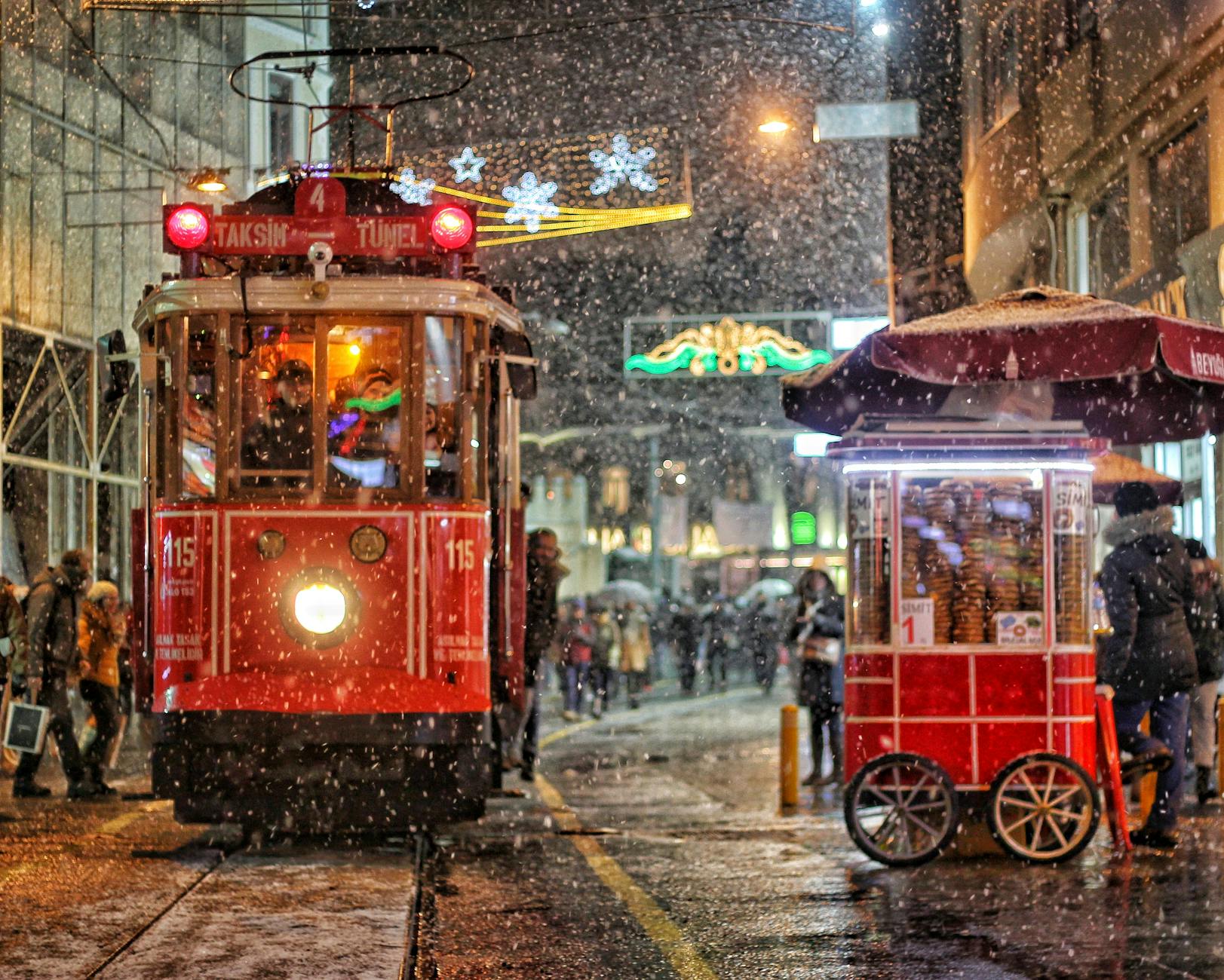 Le célèbre tramway rouge de Taksim traverse une rue enneigée près d'un kiosque.
