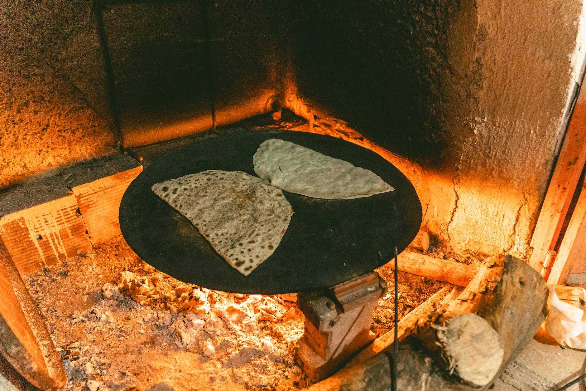 Pains plats traditionnels cuisant sur une plaque chauffante au-dessus du feu.