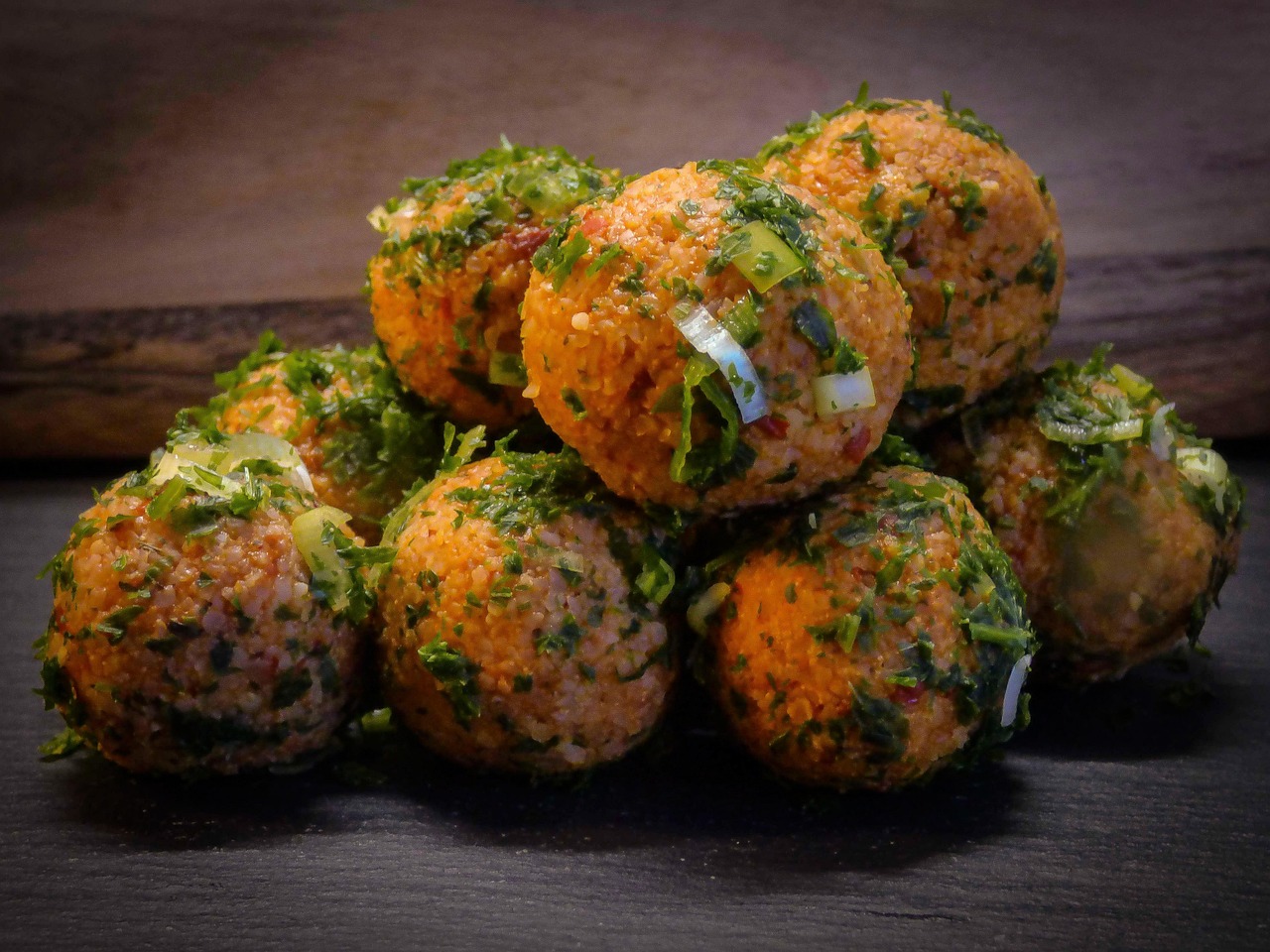 Boulettes de lentilles rouges turques appelées mercimek köftesi parsemées d'herbes fraîches.