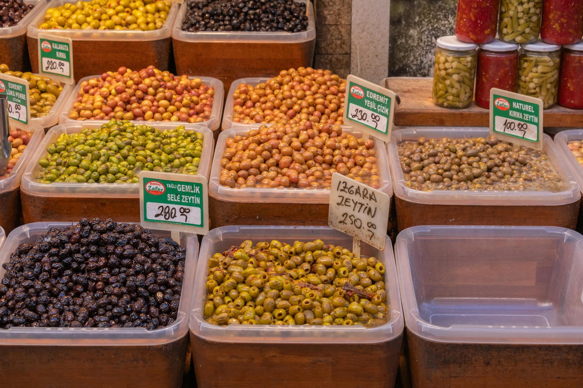 Étalage coloré de différentes variétés d'olives dans un marché de quartier.