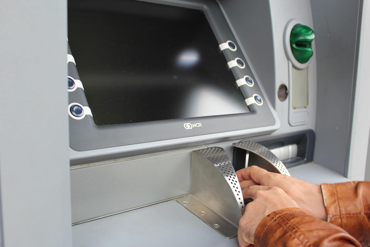 Un voyageur tape son code secret sur le clavier d'un distributeur bancaire.
